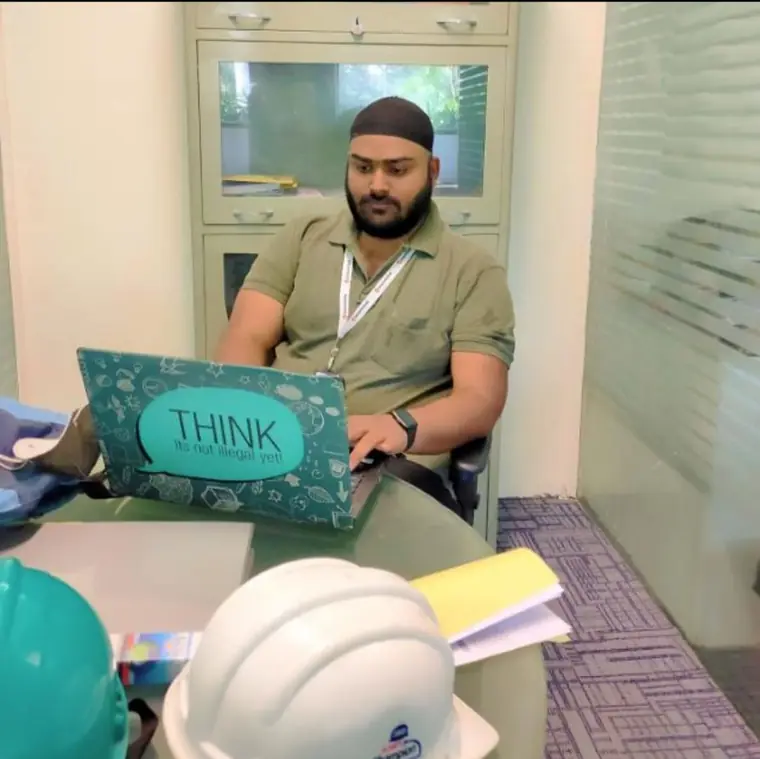 HSE consultant preparing a programme at a desk beside a safety helmet