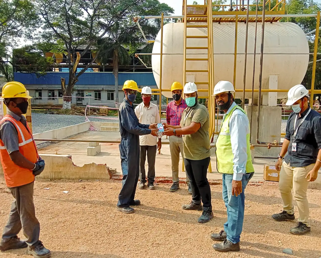 HSE Pro-Sure team in hard hats and hi-vis briefing beside a storage tank on an outdoor site
