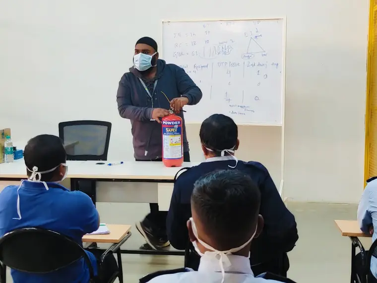 Instructor demonstrating a fire extinguisher to a seated class
